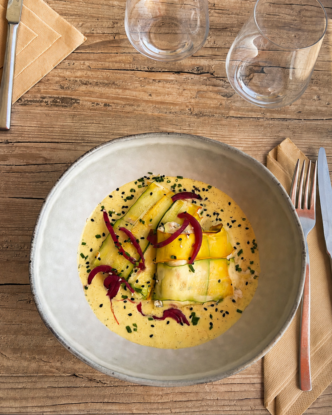 Assiette de courgettes en rubans servie sur une table en bois