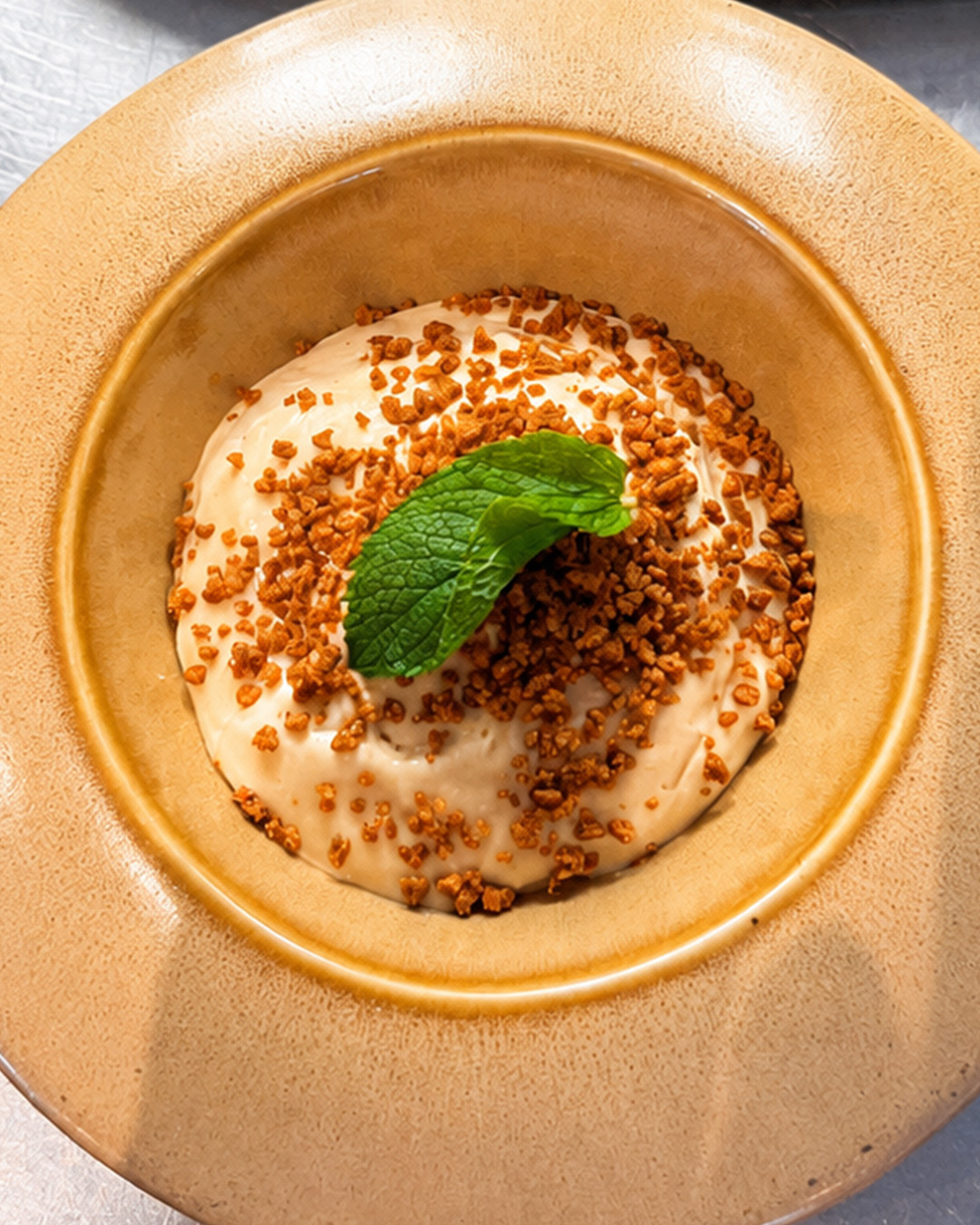 Dessert crémeux avec éclats croustillants et menthe, vu du dessus