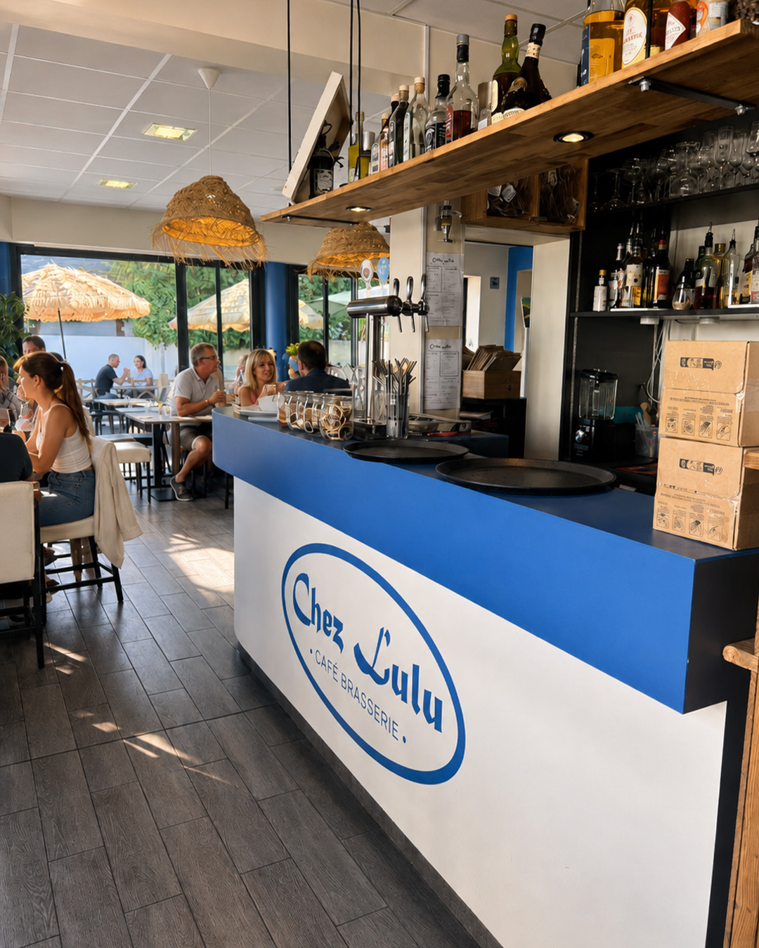 Intérieur de Chez Lulu avec le comptoir, les bouteilles et des clients attablés